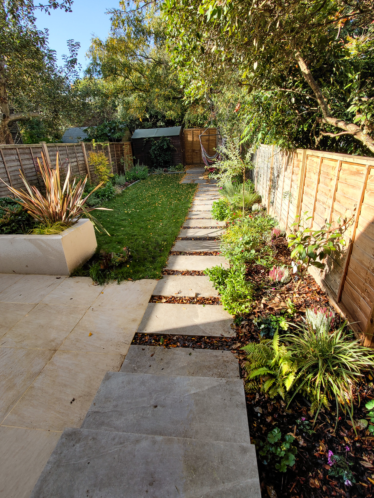 Raynes park garden with raised beds and paving, phormium, acers
